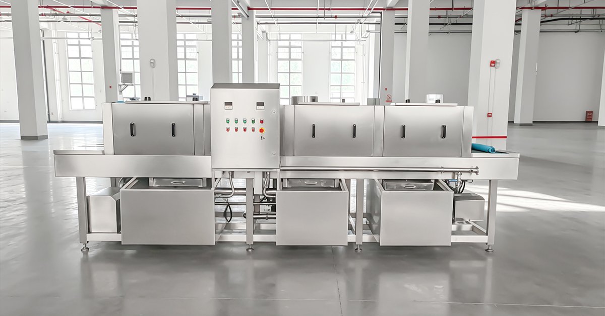 HE-3600 tunnel-type crate washing machine cleaning plastic crates in a food processing plant